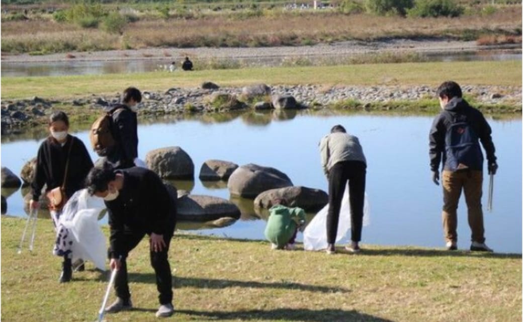 世田谷自然食品の社員が多摩川河川敷でゴミ拾いをしている写真